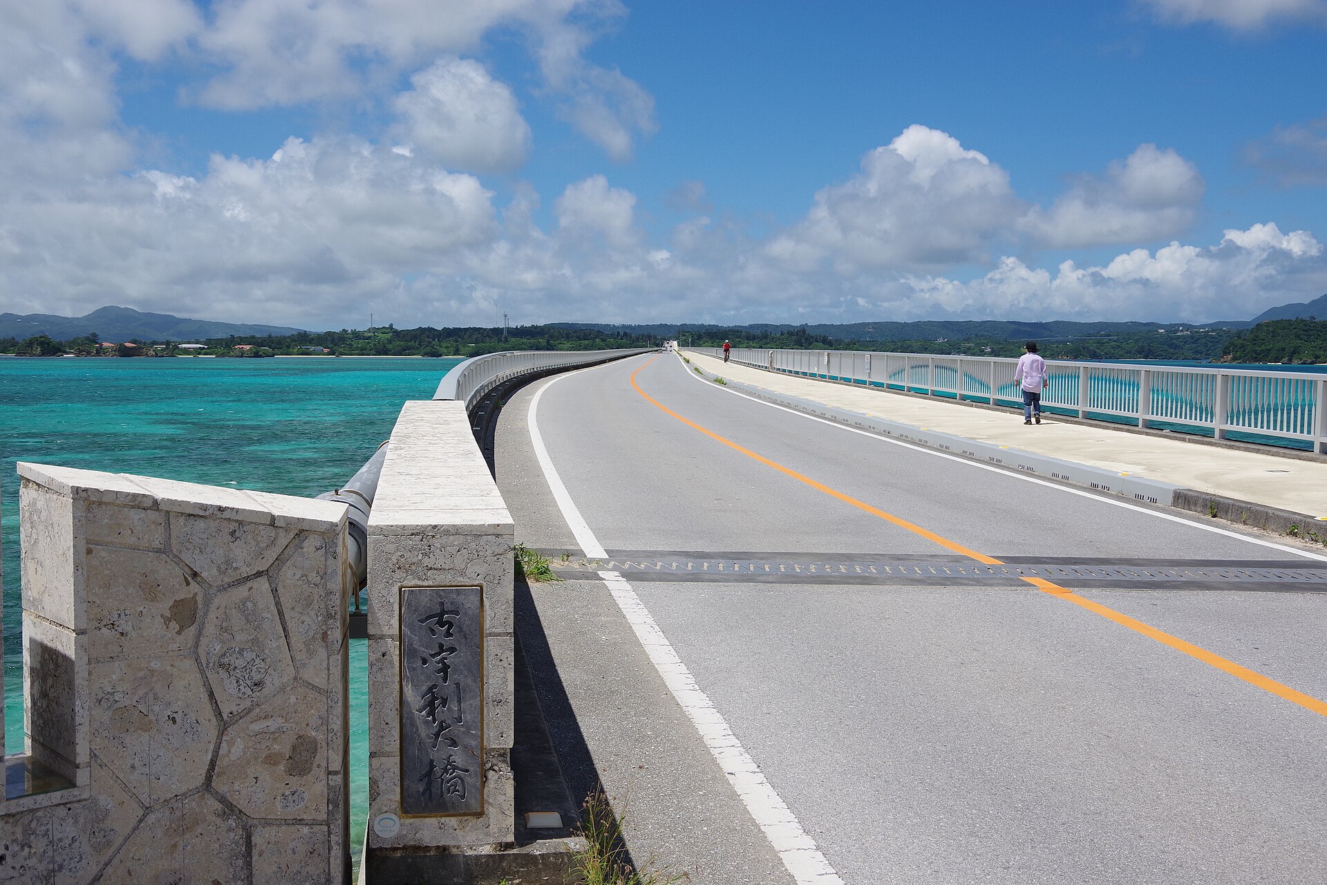 Kouri Bridge in northern Okinawa, a long road bridge running across turquoise shallow water toward a green island