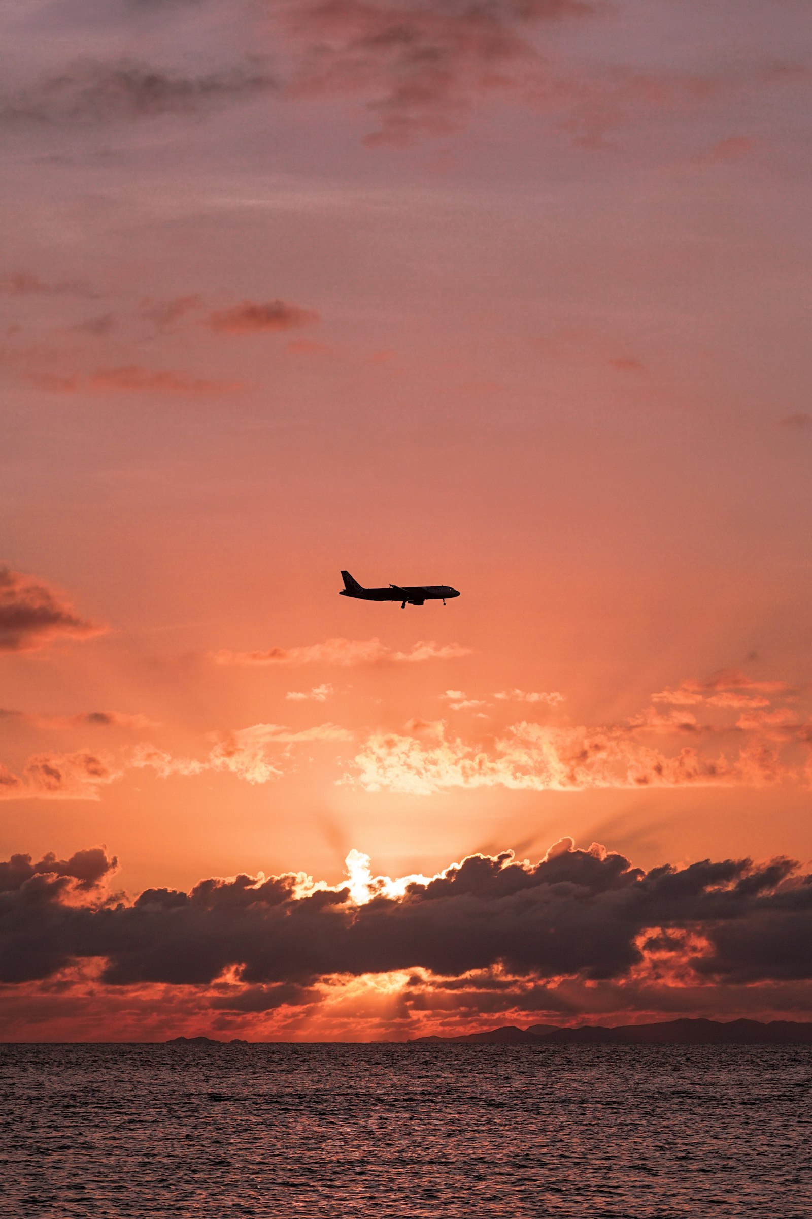 An airliner flying over the ocean at sunset near Okinawa